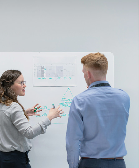 女性と男性がホワイトボードの前で話している様子